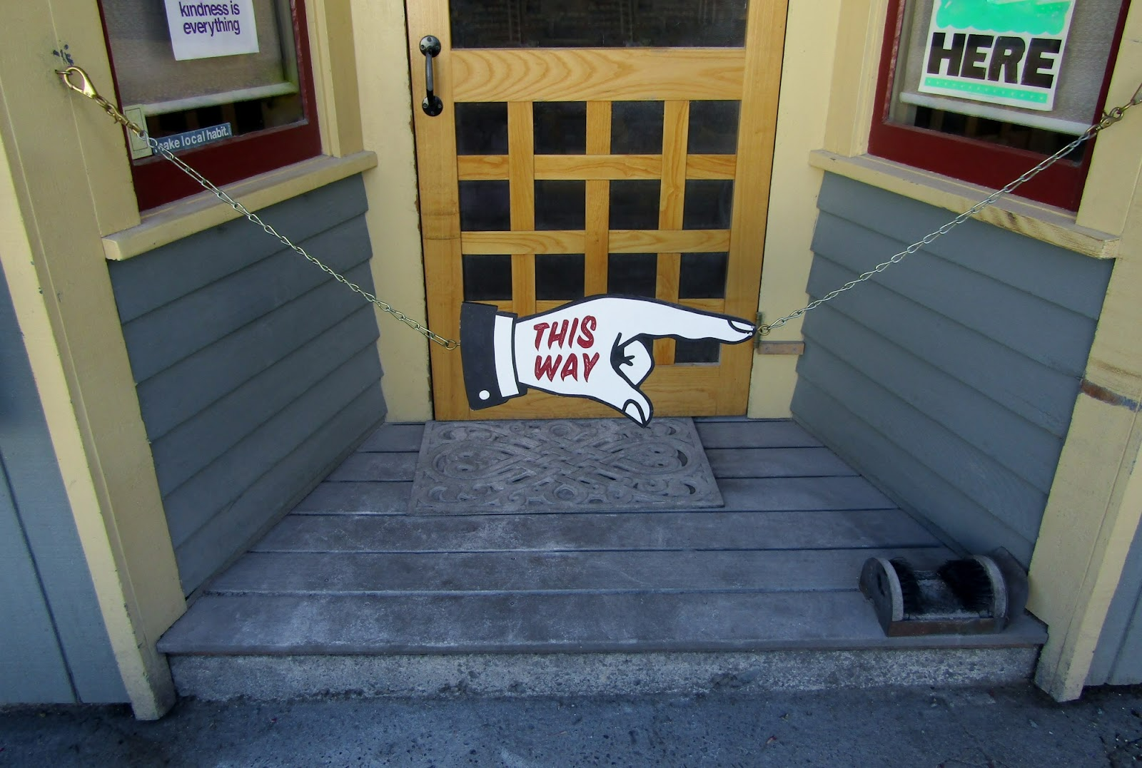  A “This Way” sign in the form of a hand pointing its finger blocks off a portion of a house.