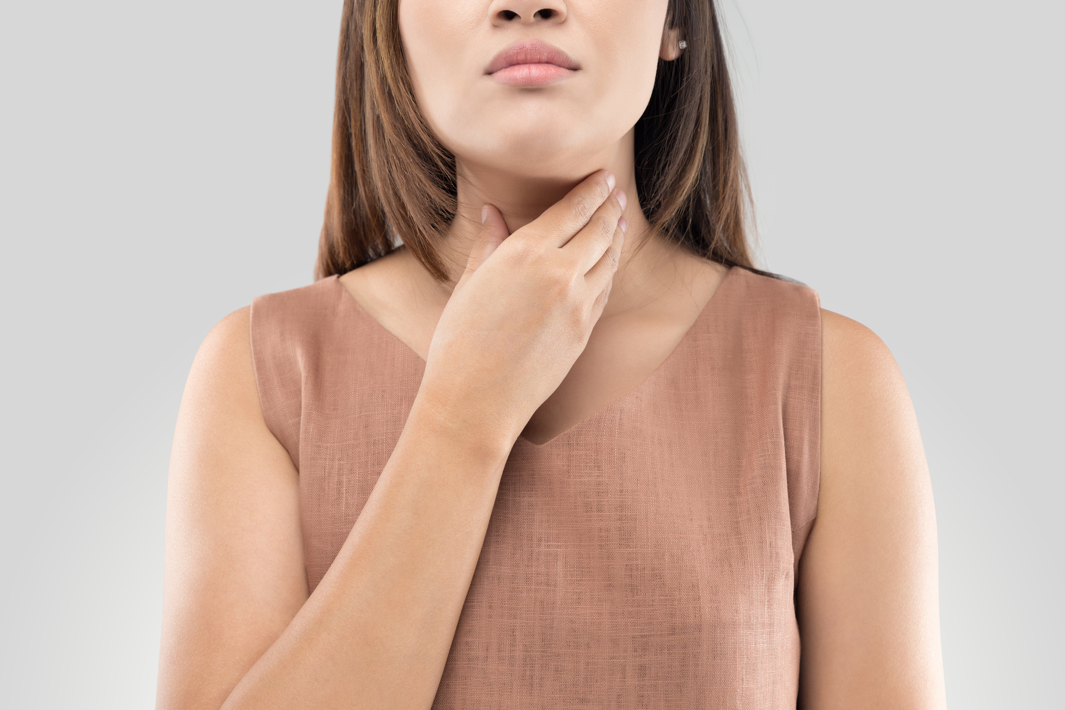 An image of a young woman with a sore throat touching her neck. 