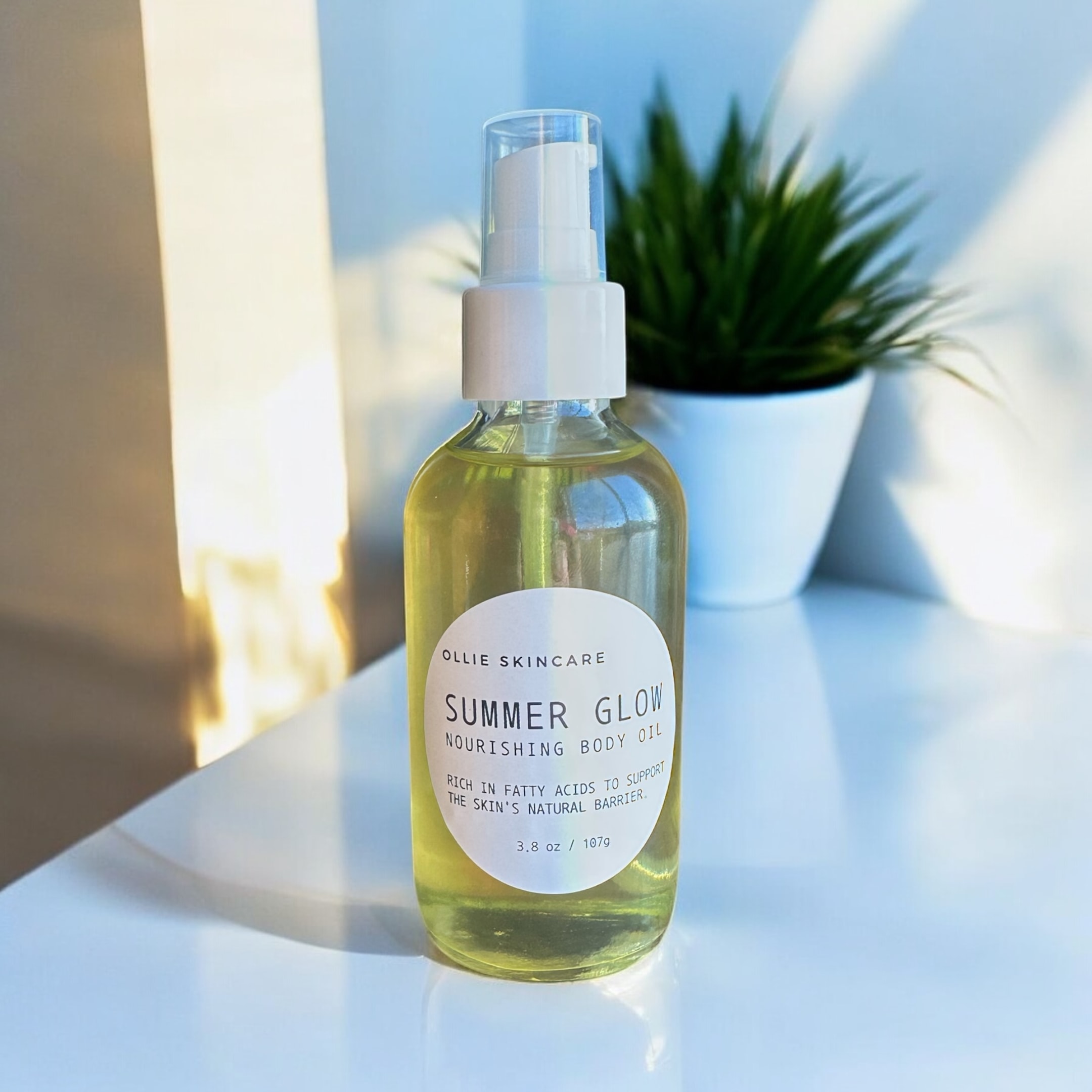The image features a bottle of Ollie Skincare body oil, showcasing its elegant design and label, surrounded by organic essential oils and natural ingredients. This body oil is ideal for practicing body oiling, promoting hydrated, smooth skin while providing many benefits for various skin types.