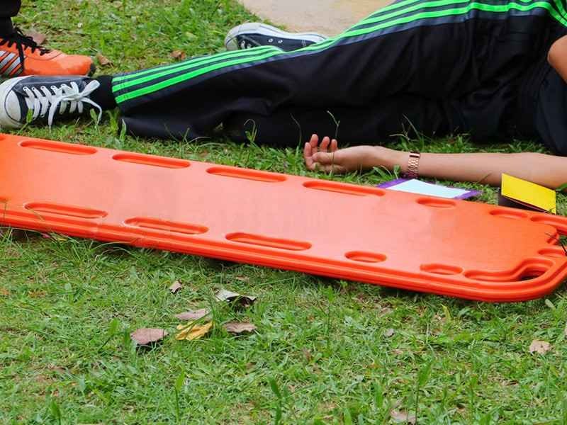 A Patient lying next to orange backboard.