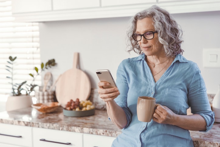 Woman with gray hair and glasses looking at a cell phone