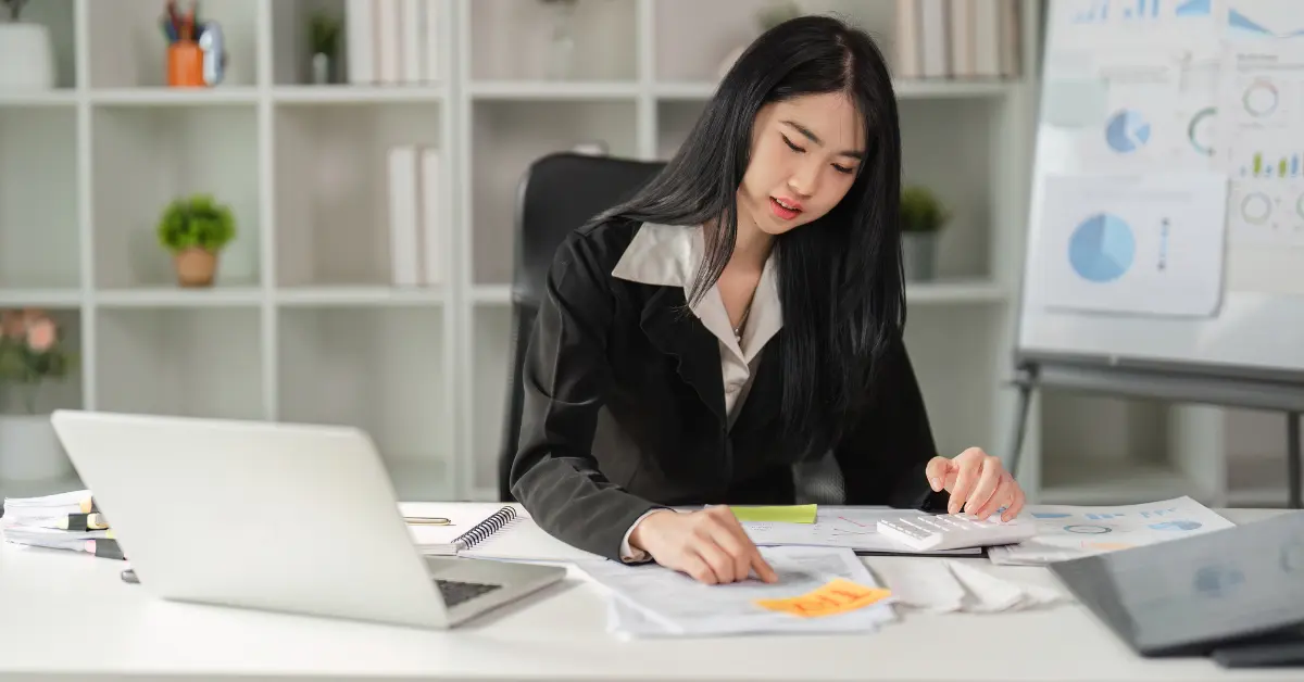 A woman reviewing tax documents and calculating quarterly taxes with audit support resources on her desk.