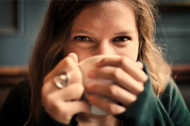 An image of a happy young woman drinking a cup of tea. 