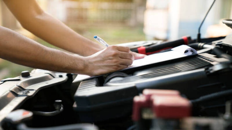 A professional inspecting the components of a car to reduce radio interferance. 