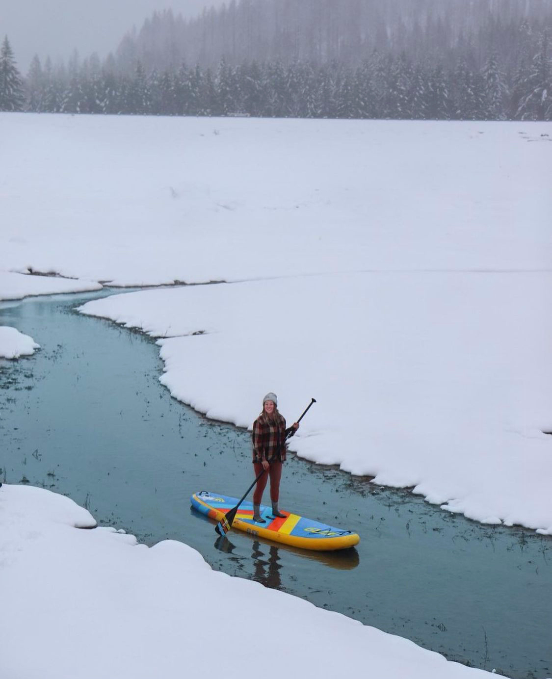 woman on inflatable paddle board in winter