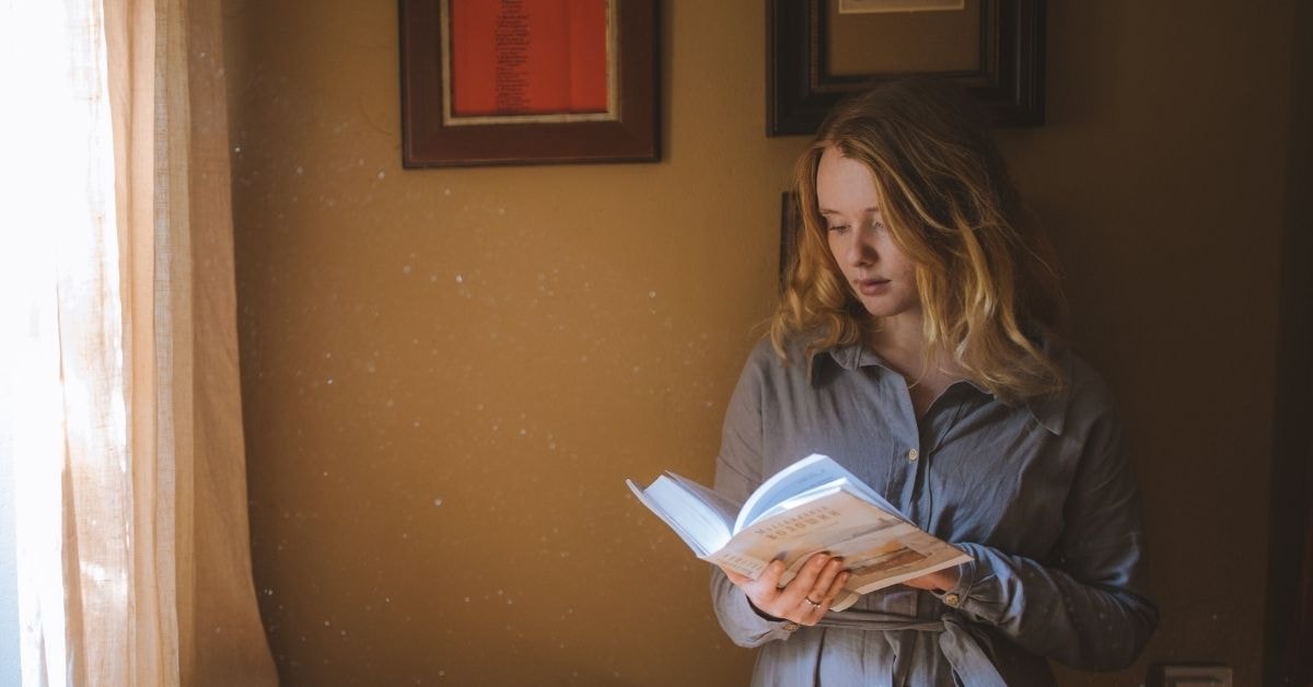 A woman studying a book in a cozy room, preparing for the 2024 tax guide and financial planning.