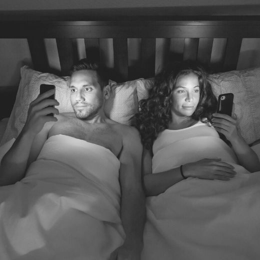 Couple in bed on their smart phones