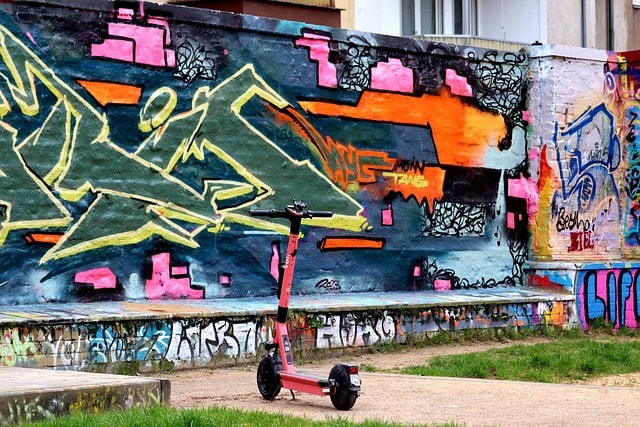 An electric scooter against a graffiti wall.