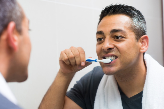 Man brushed teeth after tooth implants to maintain the health of the implant site