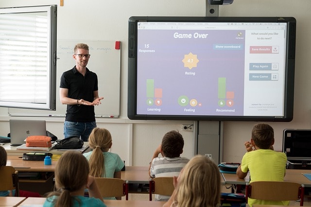 Teacher next to a large screen teaching elementary school children