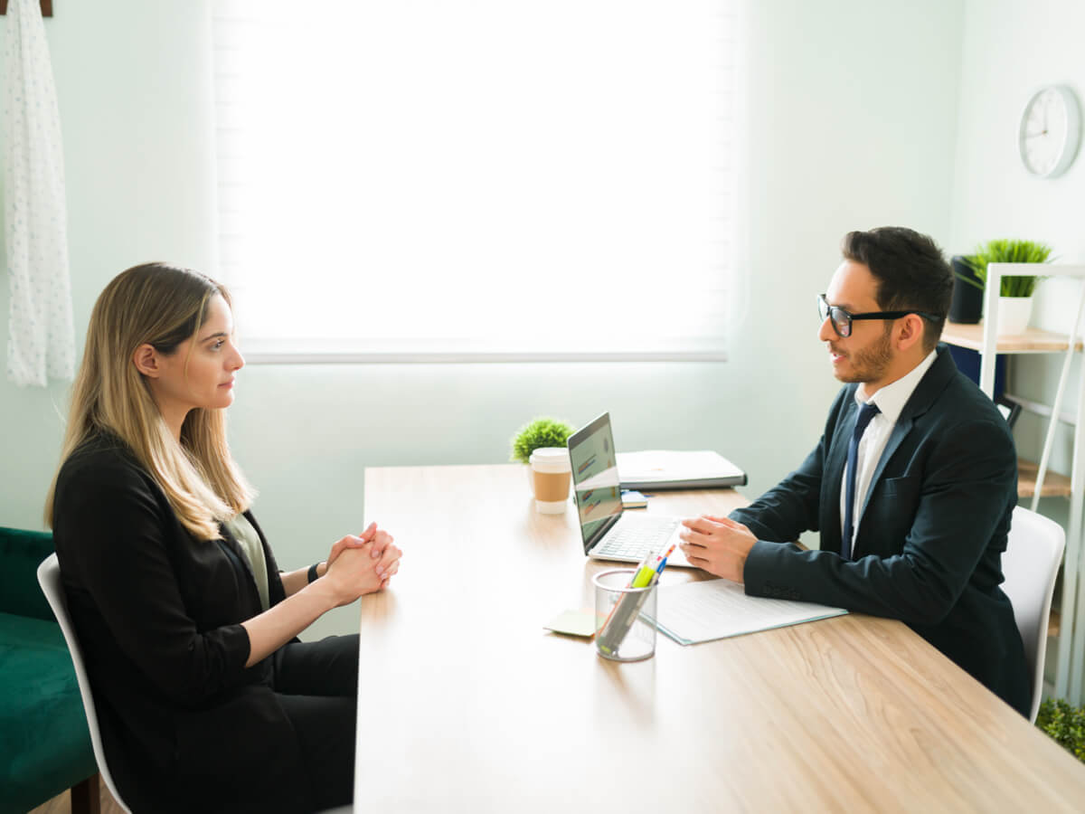 a woman and man sitting together at a desk having a discussion over a laptop