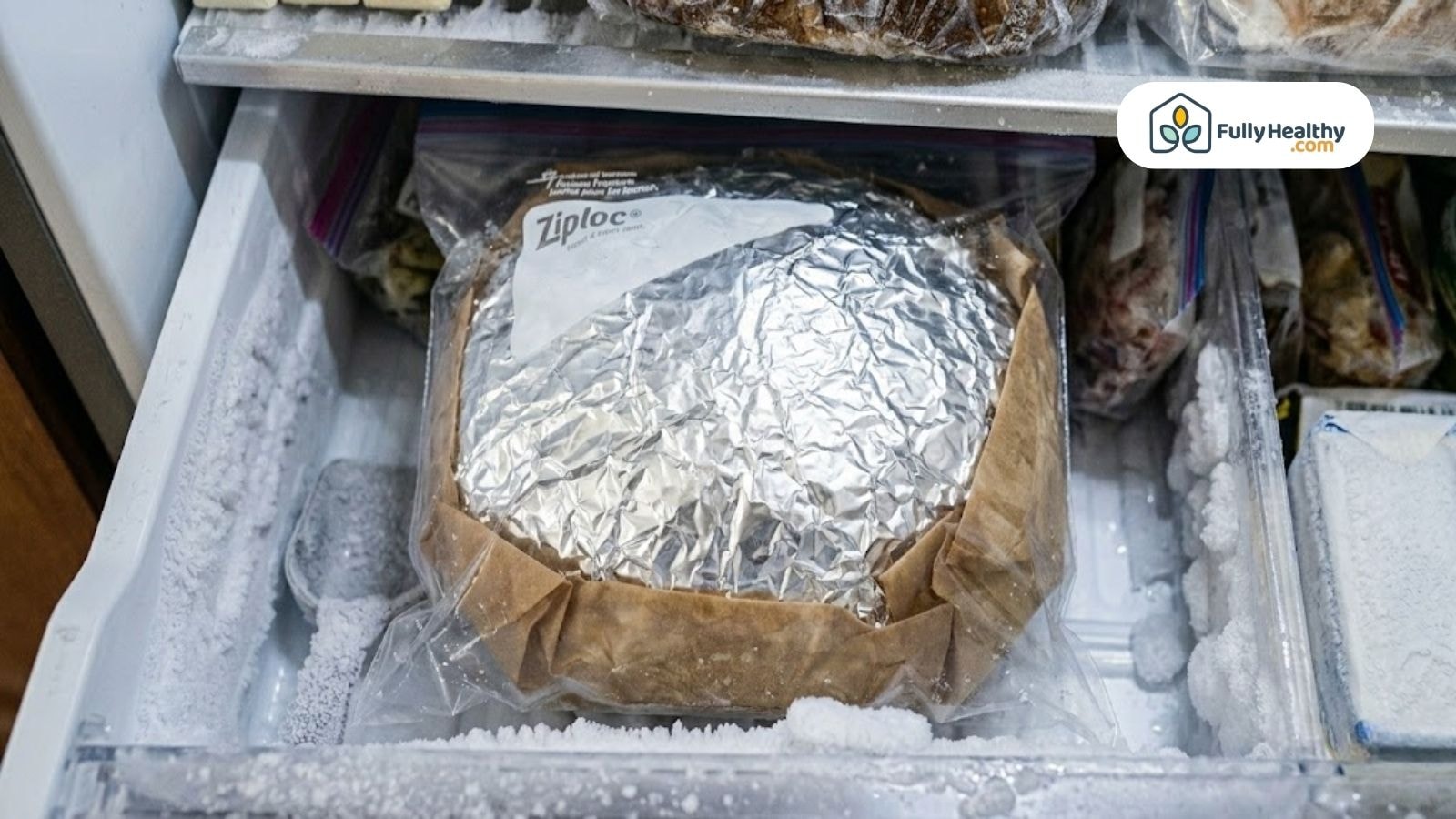Wrapped sourdough loaf inside freezer drawer sealed in foil and ziplock bag.