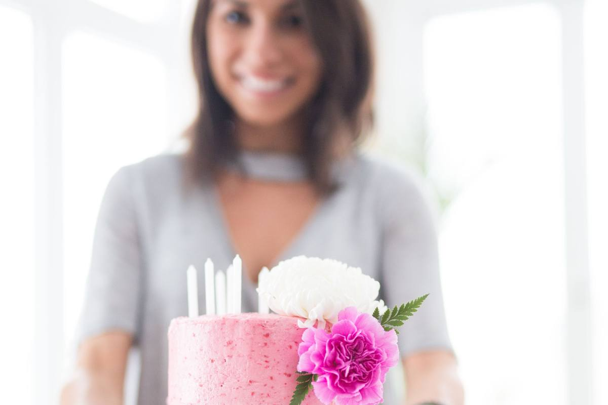 smiling woman with pink cake and pink carnation giving it to a wonderful friend, an amazing person with a heartfelt birthday message - Fabulous Flowers
