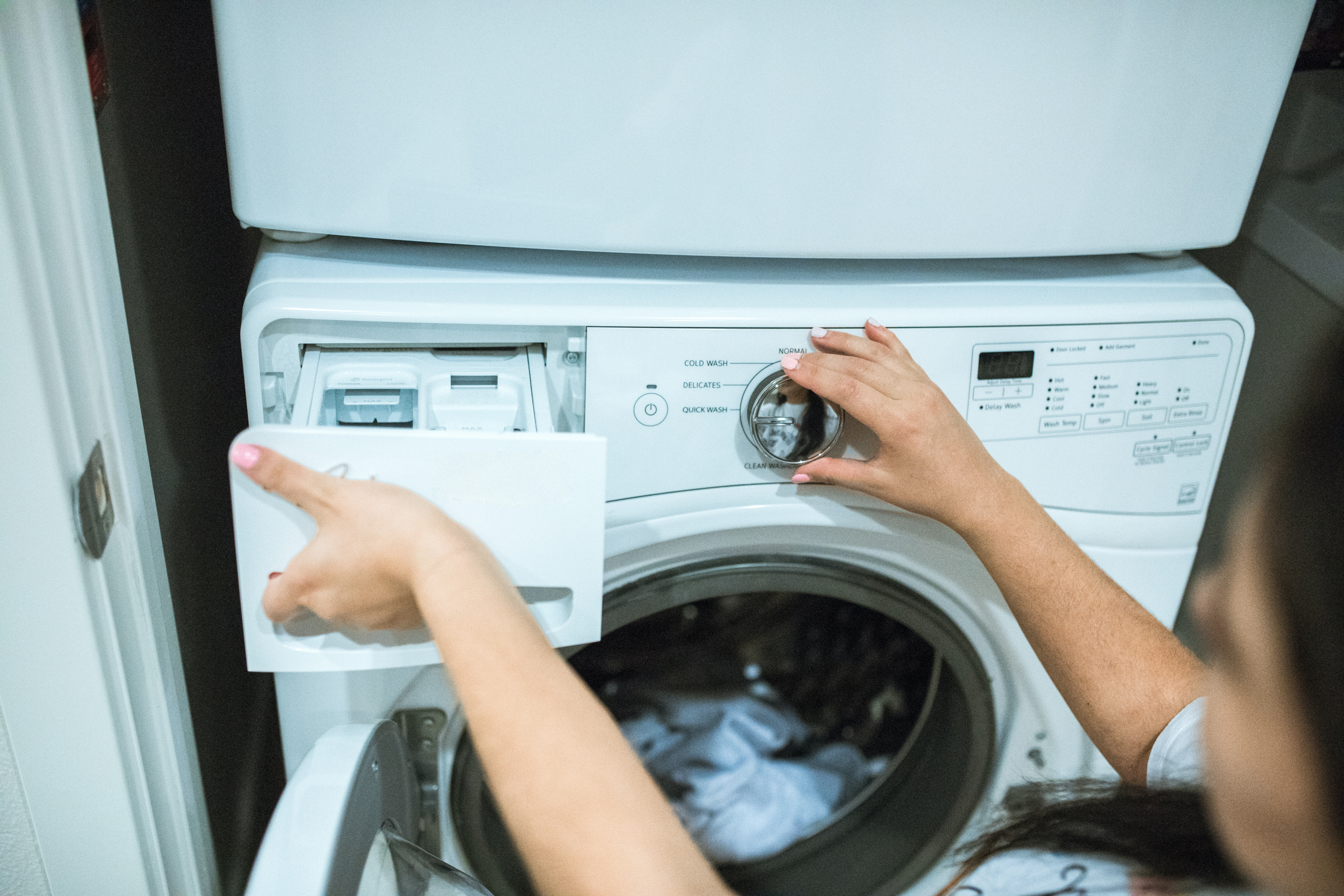 Tenant washing clothes by inserting laundry detergent into their washer 