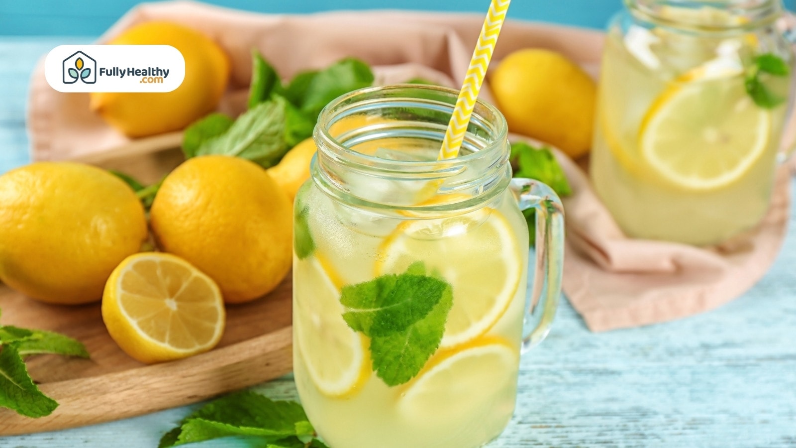 Mason jar of lemonade with mint and lemons on blue table