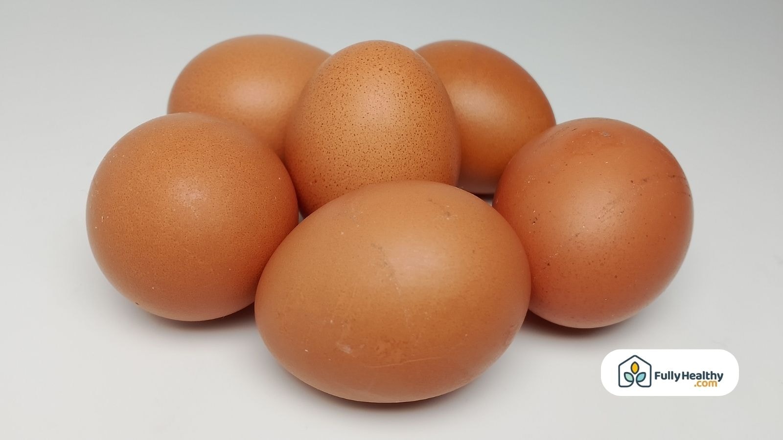 Six brown chicken eggs grouped together on clean white surface