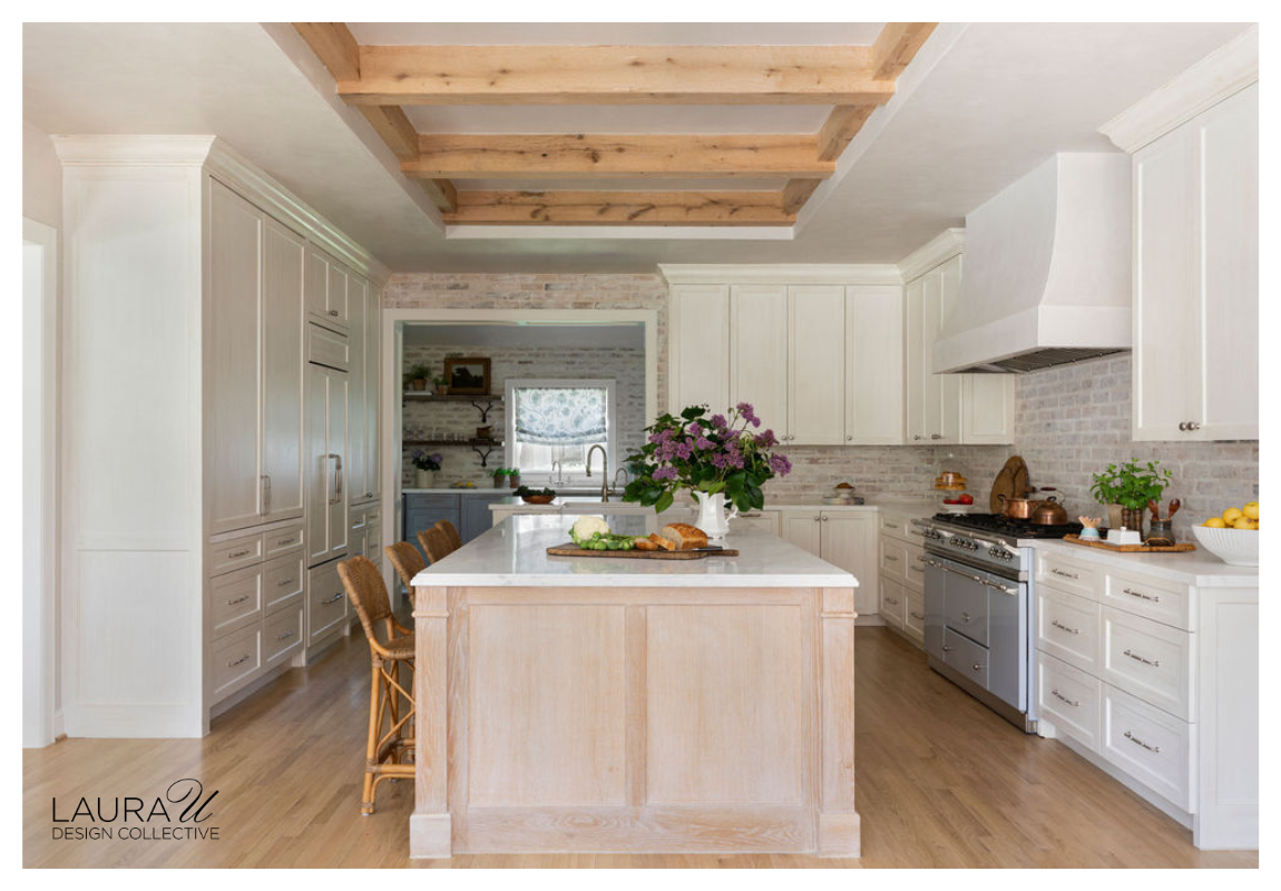 Renovated kitchen with custom island, pantry cabinetry, exposed ceiling beams, and plaster range hood.