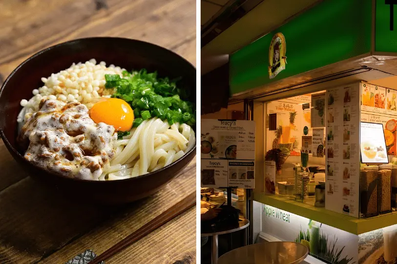 A split image displaying a hearty, rustic bowl of thick udon noodles topped with natto, scallions, puffed rice, and a raw egg yolk on the left, paired with the brightly lit, vibrant green storefront of a juice and smoothie bar on the right.