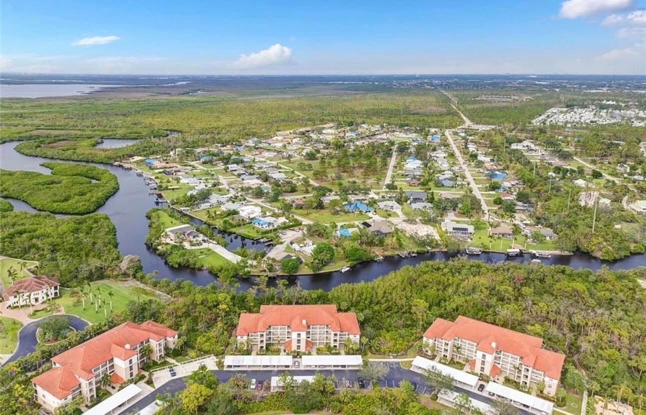 The image depicts scenic waterfront homes along the Estero River, showcasing charming boat docks and lush natural vegetation that enhances the serene atmosphere. This area, known for its Estero River Heights real estate, offers a picturesque setting ideal for kayaking and fishing, with access to walking trails and nearby golf courses.