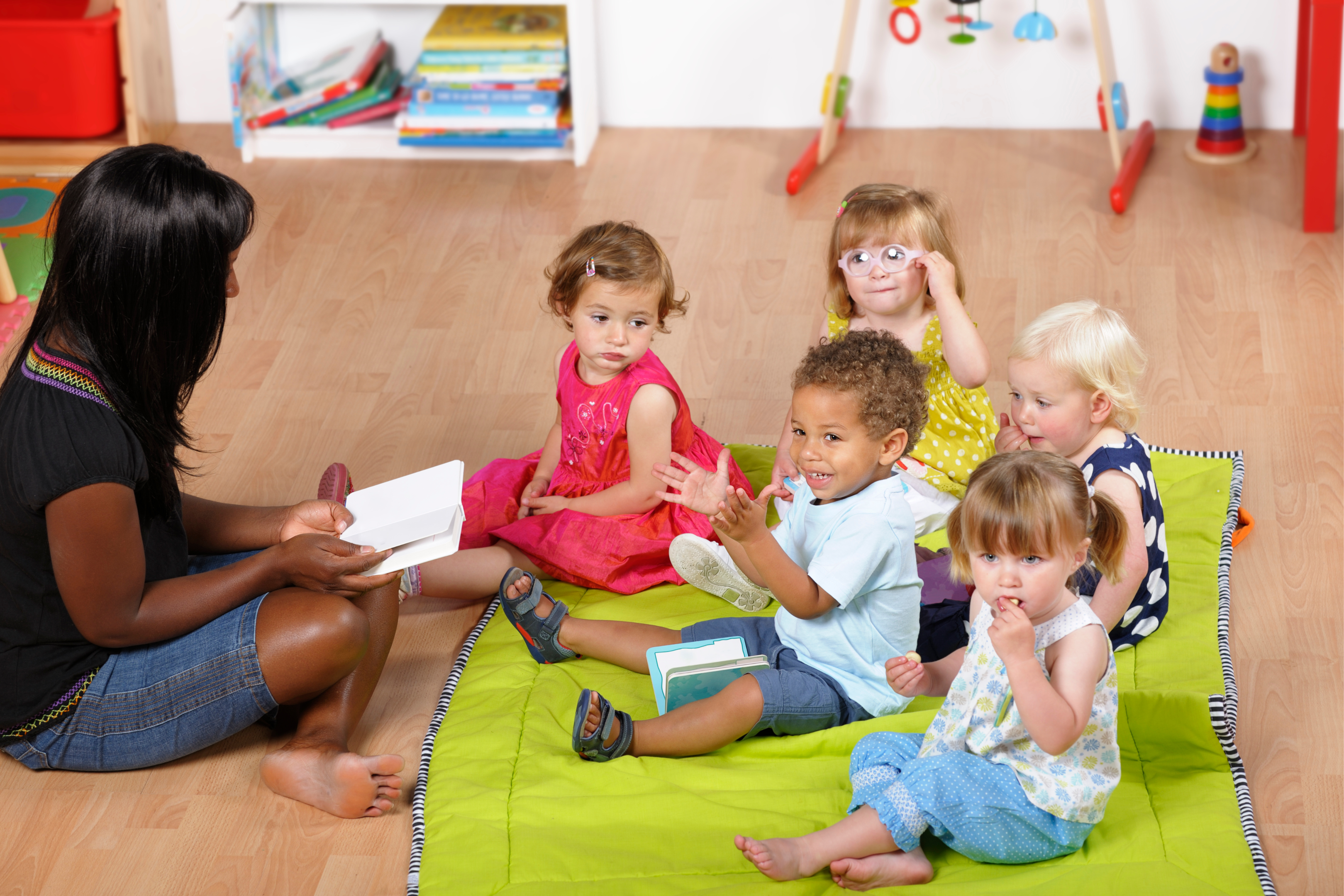 teacher on the floor reading with toddlers