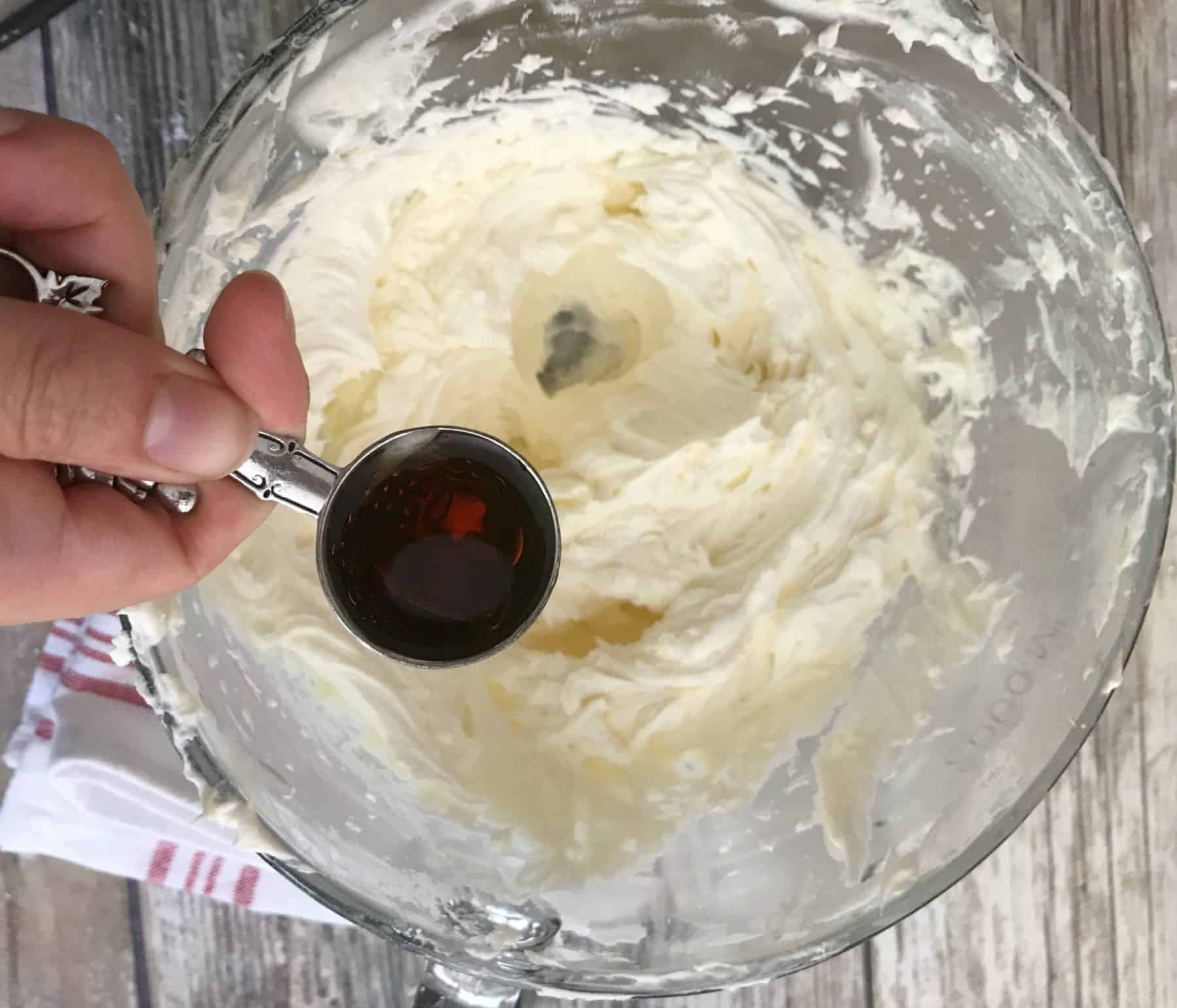 vanilla extract being added to bowl of frosting