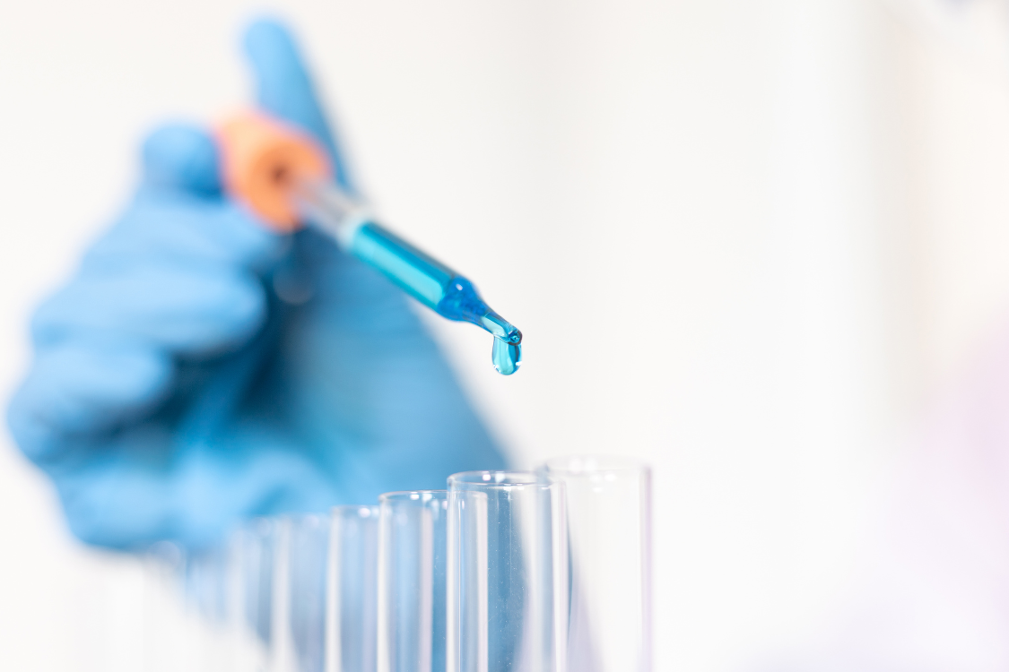 Gloved hand using a pipette to test supplement ingredients in a lab for quality assurance and safety