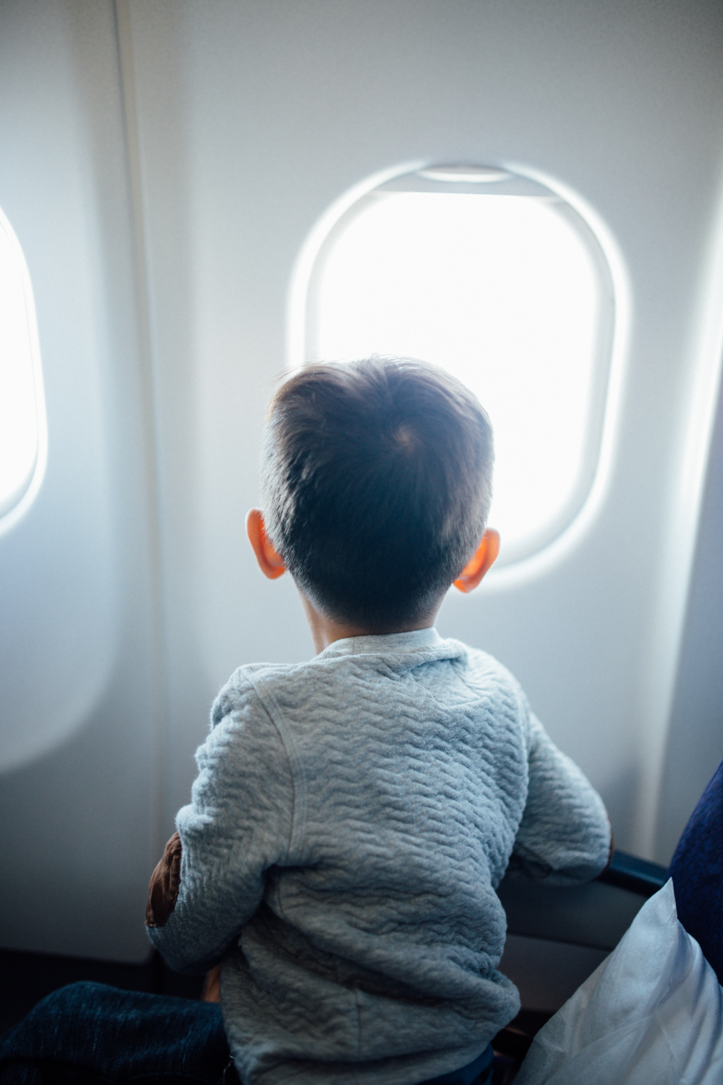 Photo of a kid looking at the window inside an airplane