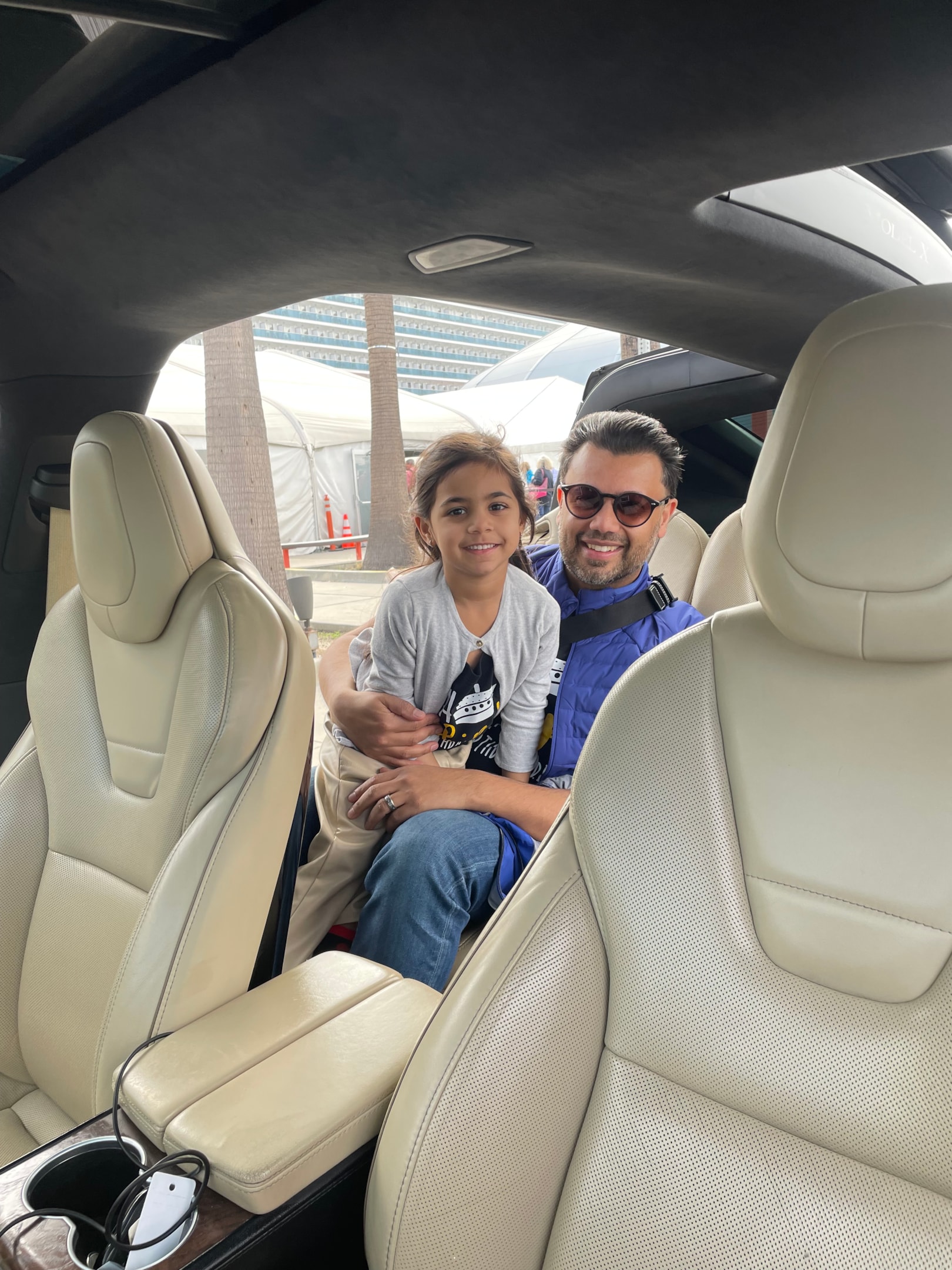 A man holding his child in his lap, a car seat is behind them.