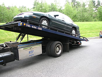 A tow truck driver picking up a junk car from a driveway