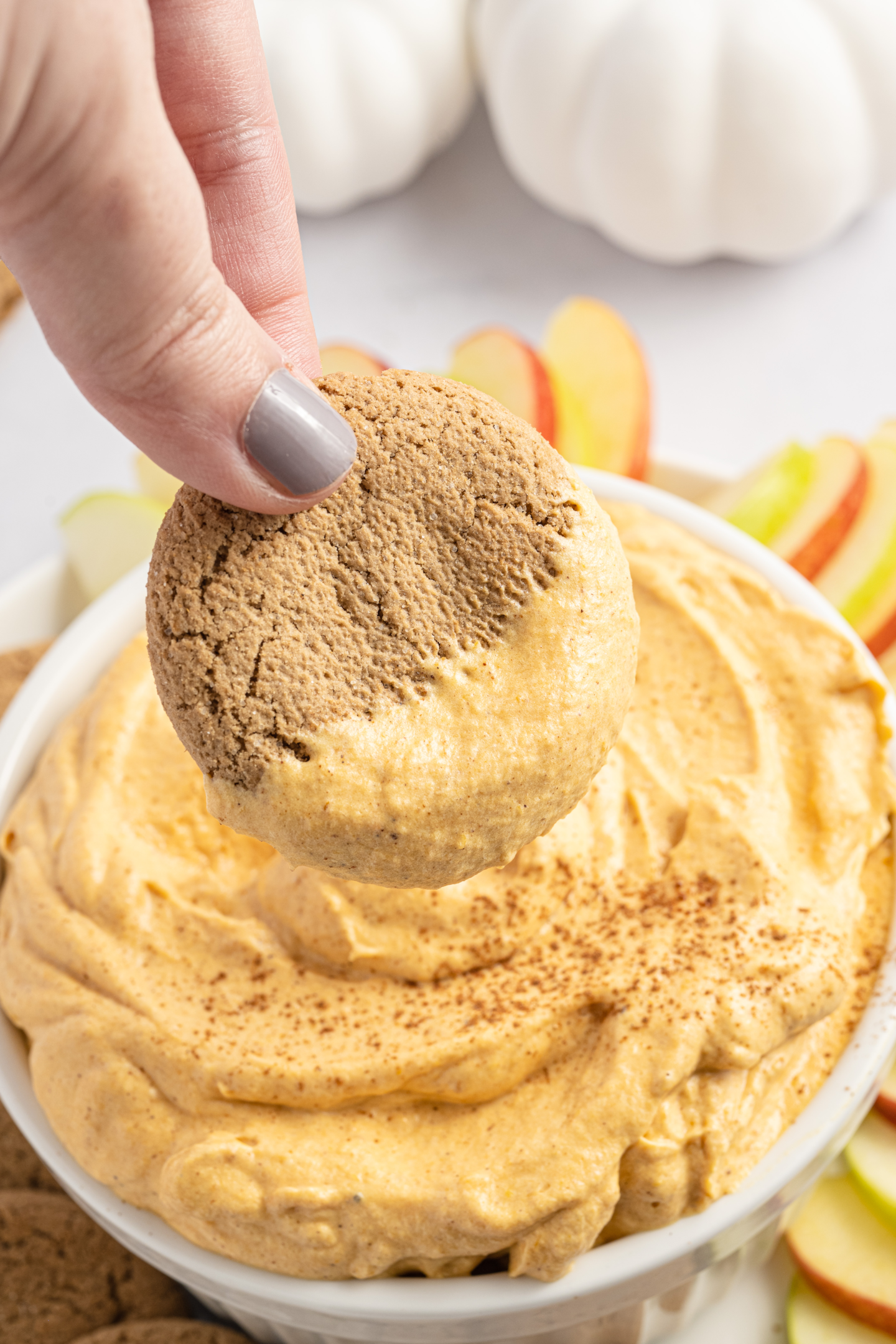 hand scooping pumpkin dip with a gingersnap cookie