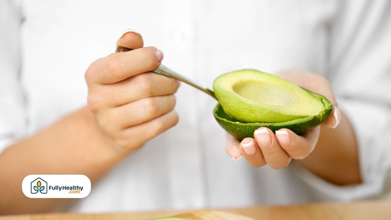Person holding avocado half and scooping with spoon