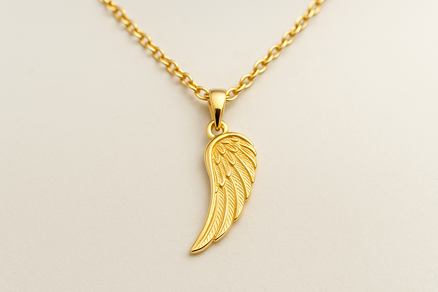 Auksinė grandinėlė su angelo sparno pakabuku ant šviesaus fono