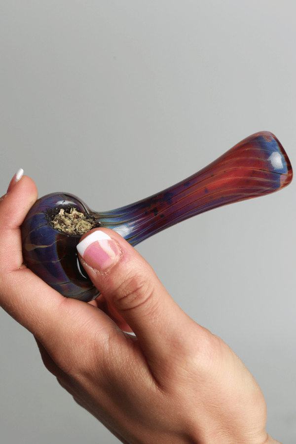 a woman holding a glass weed pipe