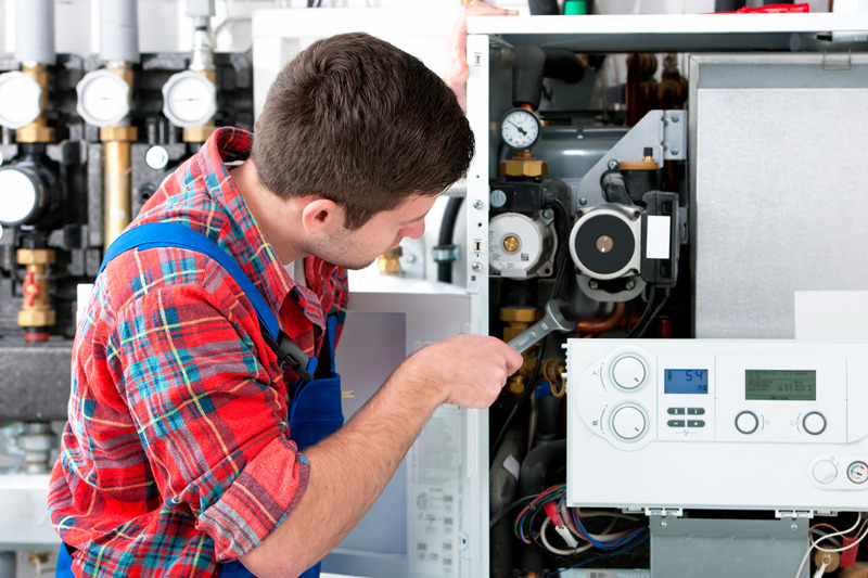 Ein Installateur arbeitet konzentriert an einer Heizung.