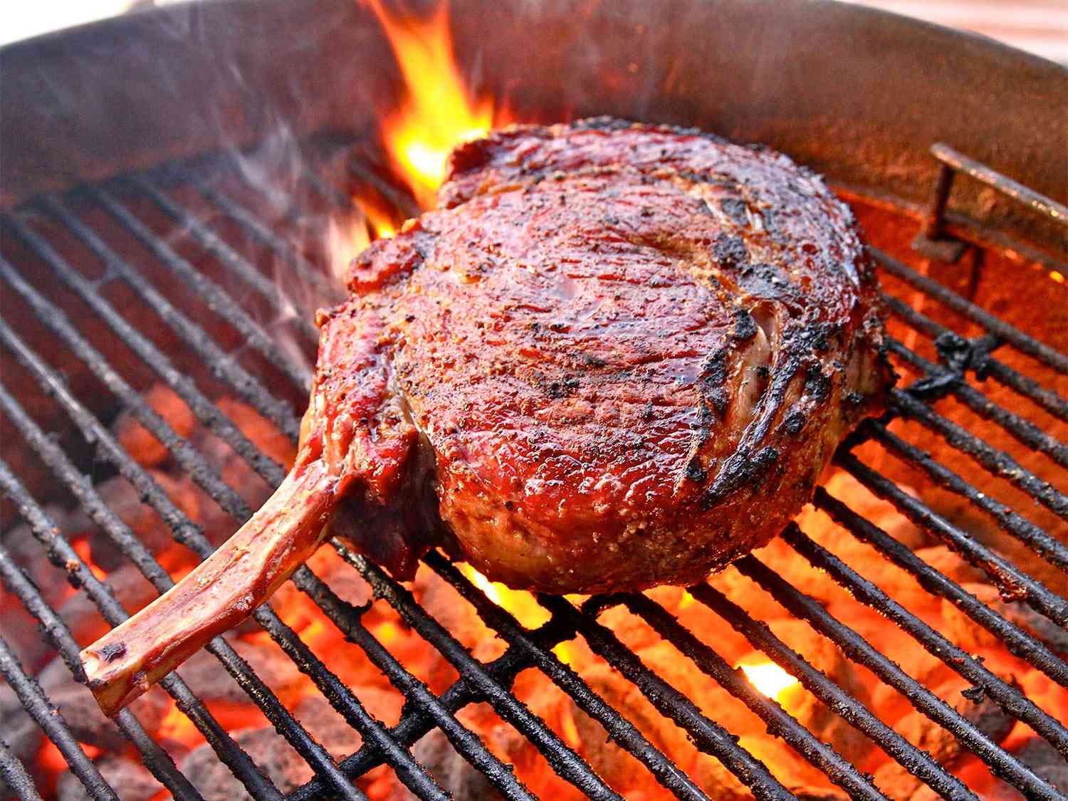 big piece of steak on a massive fiery bbq