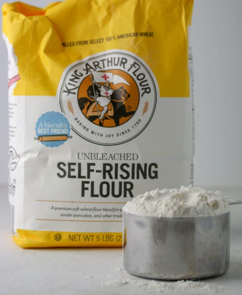 bag of self rising flour and a measuring cup filled with flour
