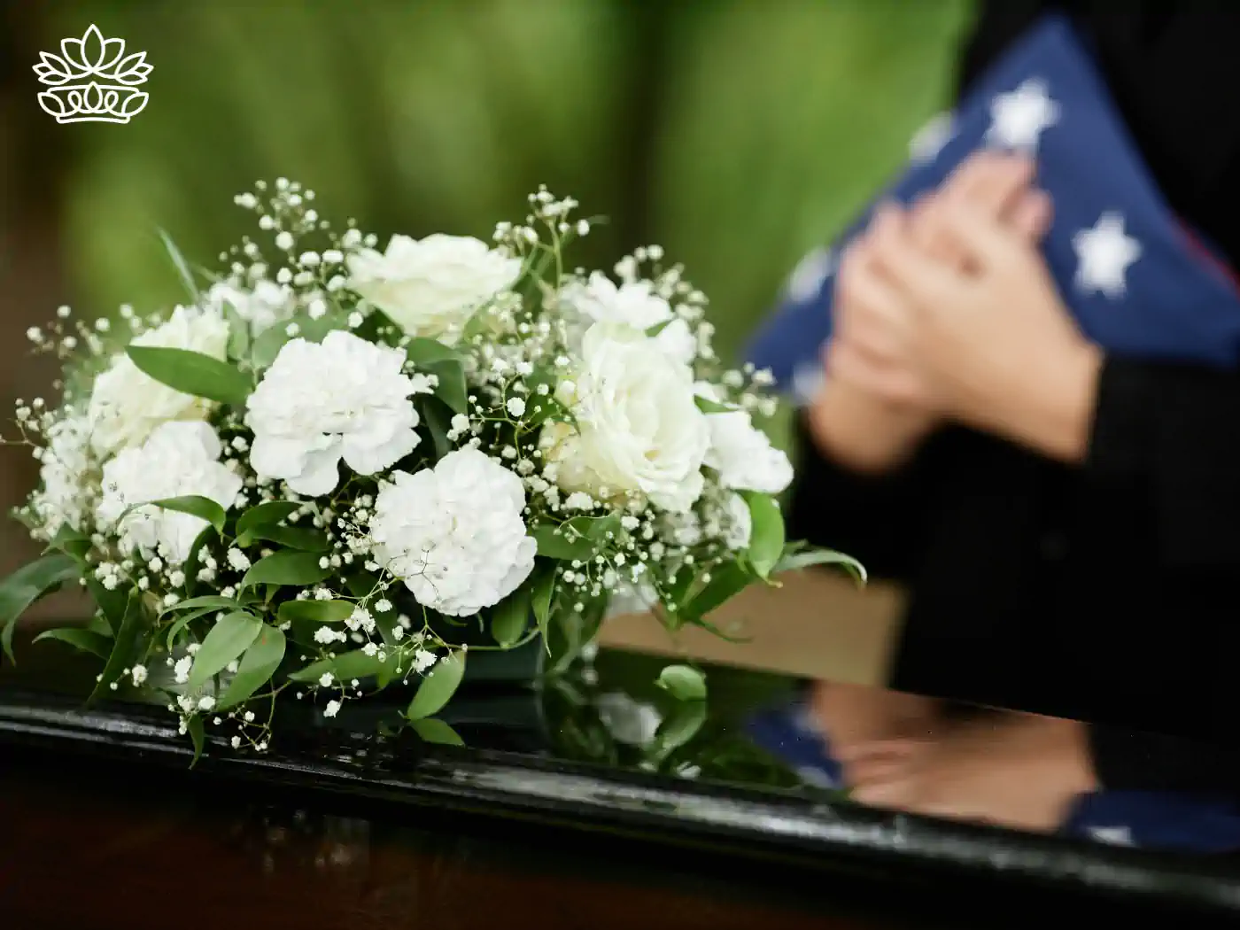 White flower bouquet placed on a casket during a funeral ceremony. Fabulous Flowers and Gifts Funeral Collection.