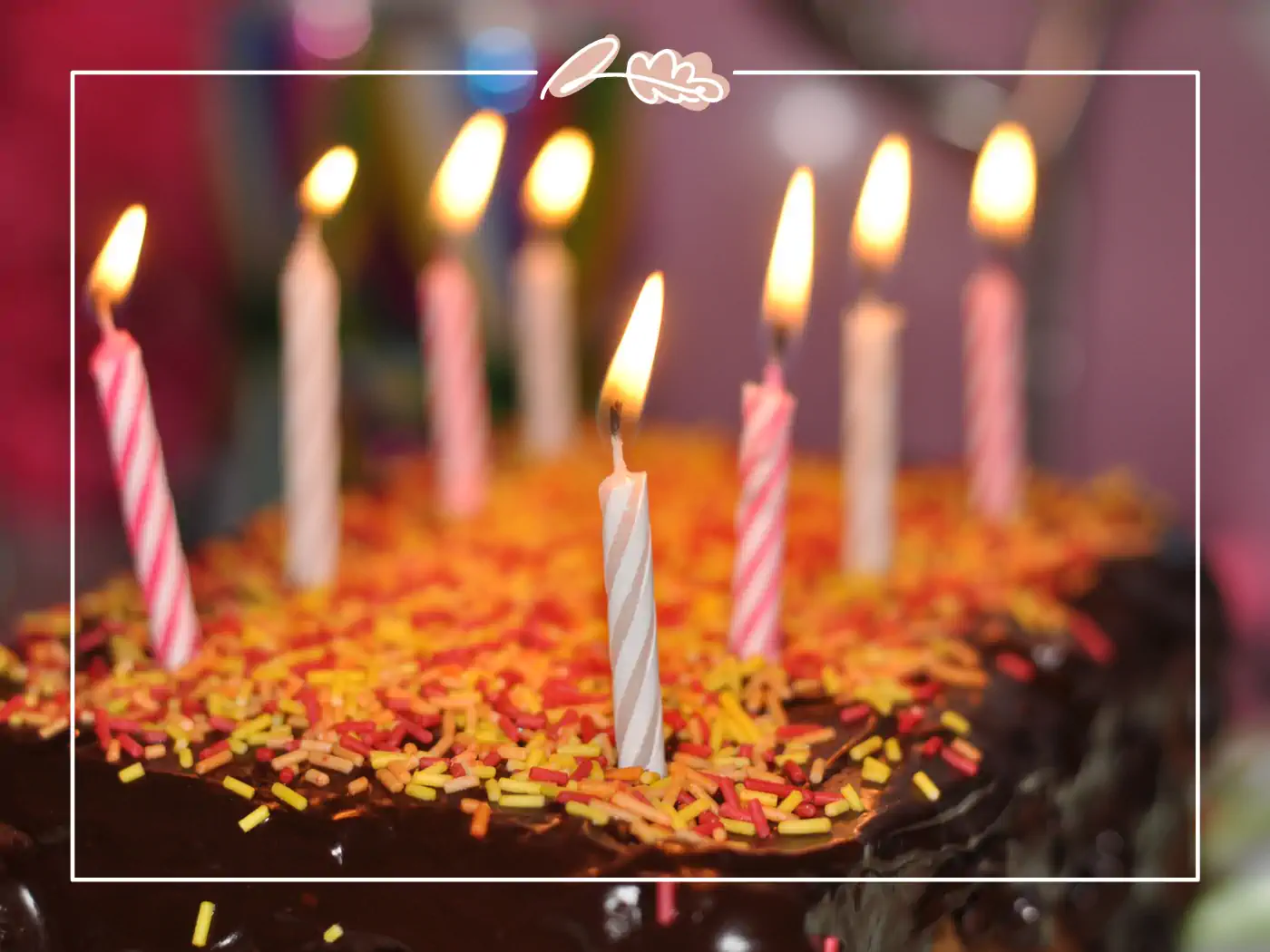 Chocolate birthday cake with lit candles, fabulous flowers and gifts