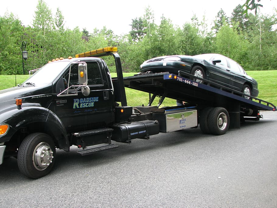 A junk car being towed away by a tow truck driver