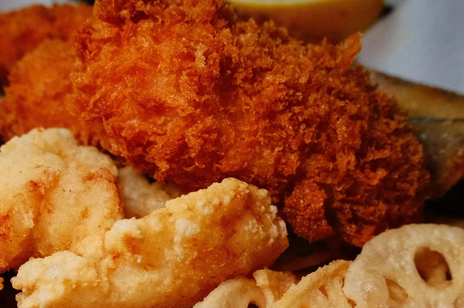 A close-up of crispy fried fish fillet, with a side of fried calamari and lotus root chips.
