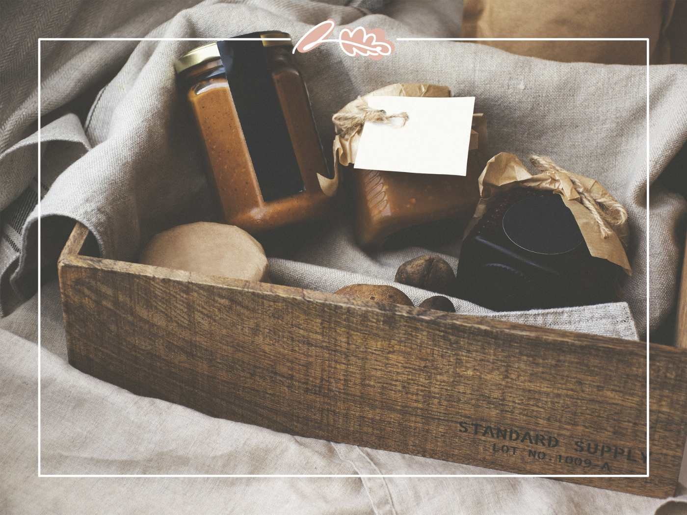 Wooden crate filled with jars and wrapped soaps on fabric.