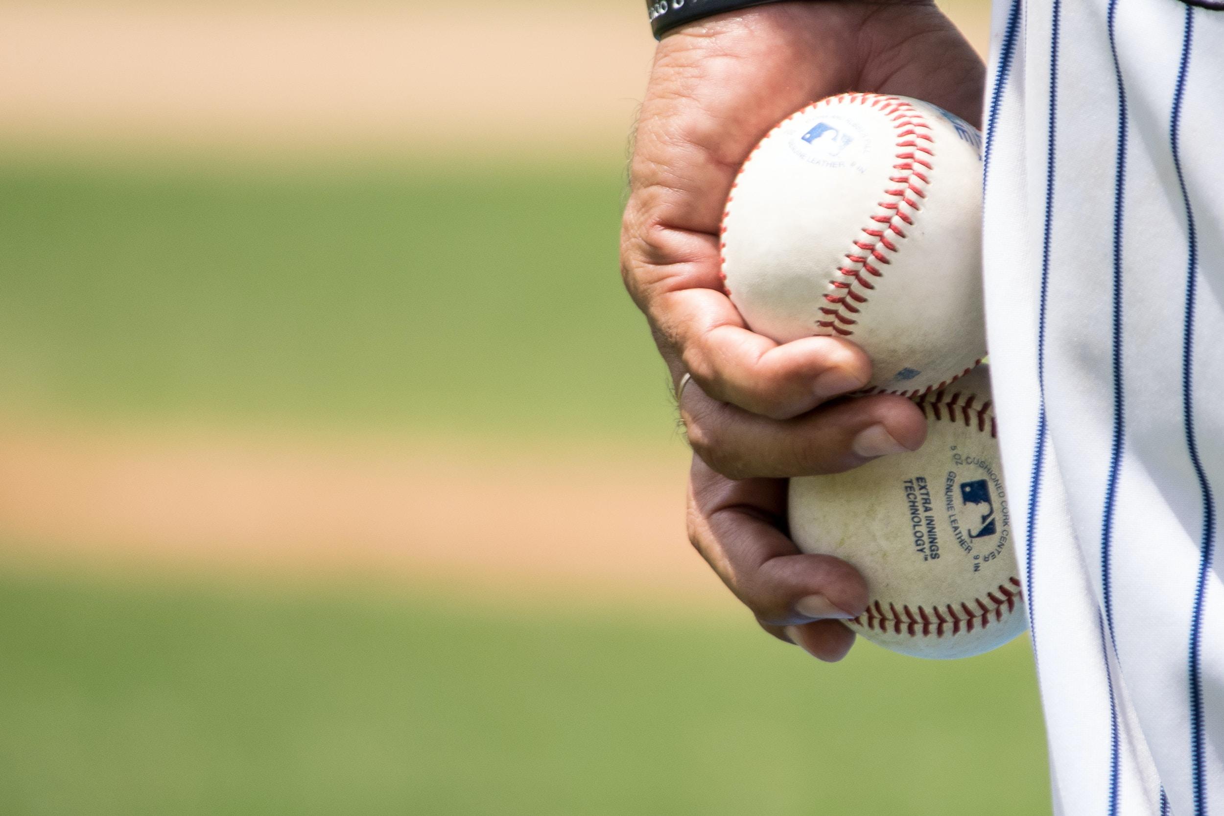 A pitcher holding 2 MLB Baseballs