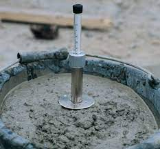 A person using a K slump tester to measure the consistency of wet concrete