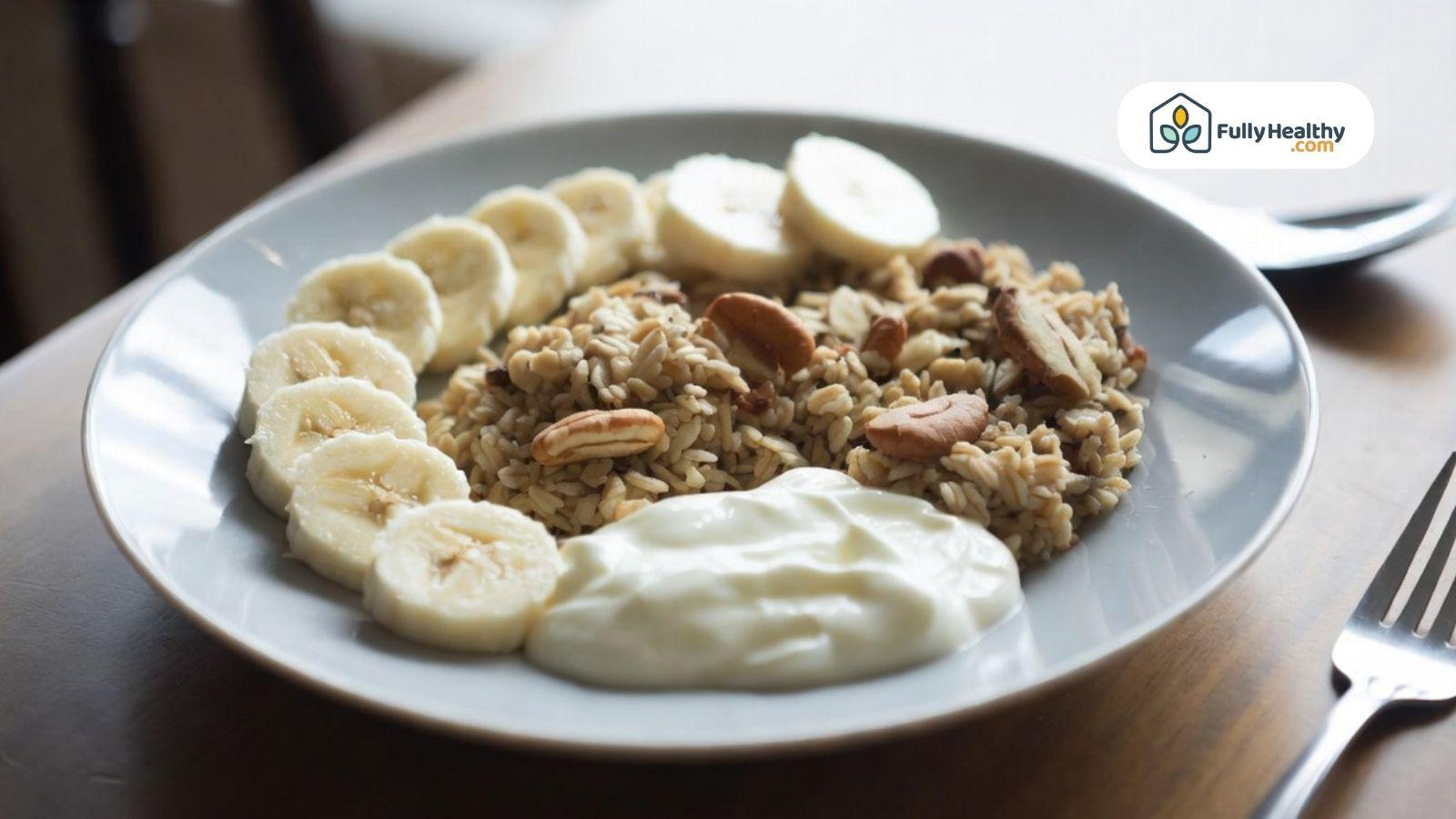 Bowl of oats topped with banana slices, nuts, and yogurt on a plate.