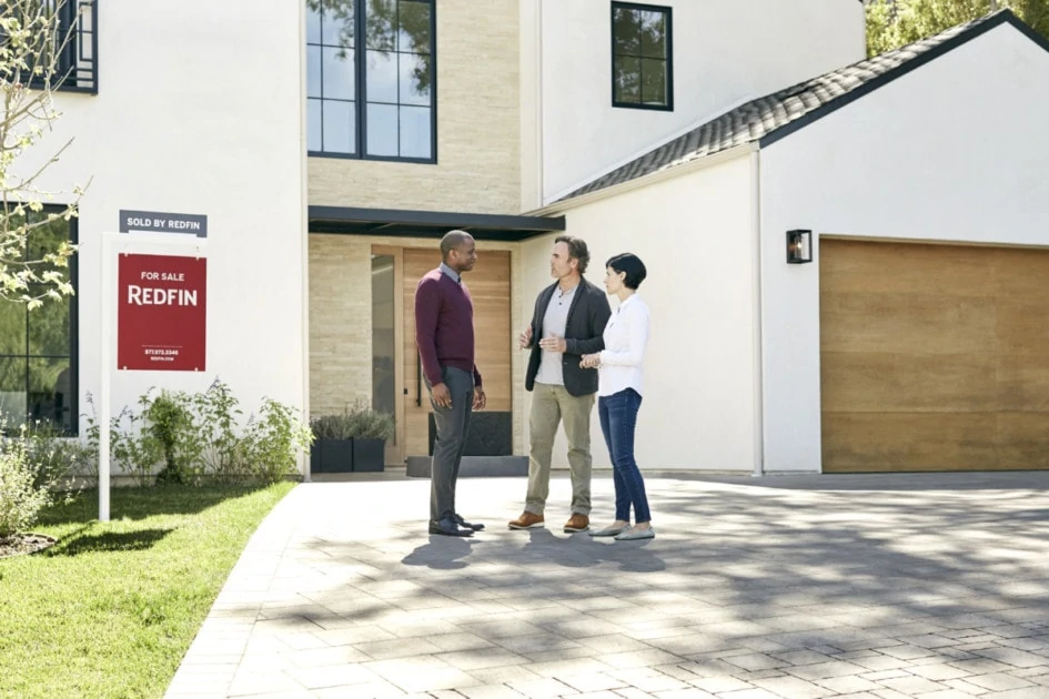 realtor standing outside of a home with a couple: how to choose a realtor