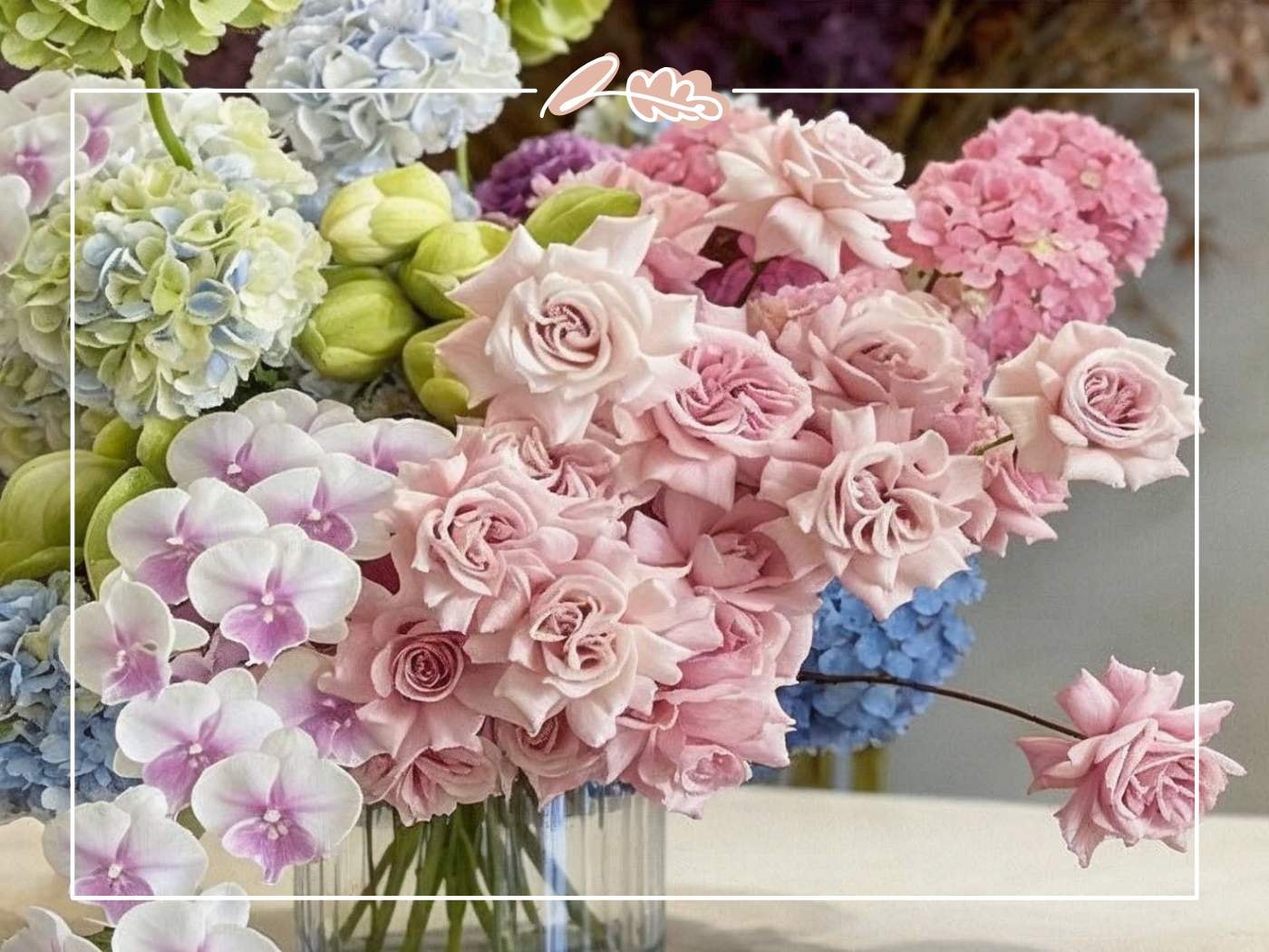 Close-up of a hydrangea and rose arrangement showing blush pink roses nestled among blue and pink hydrangea blooms with orchid accents