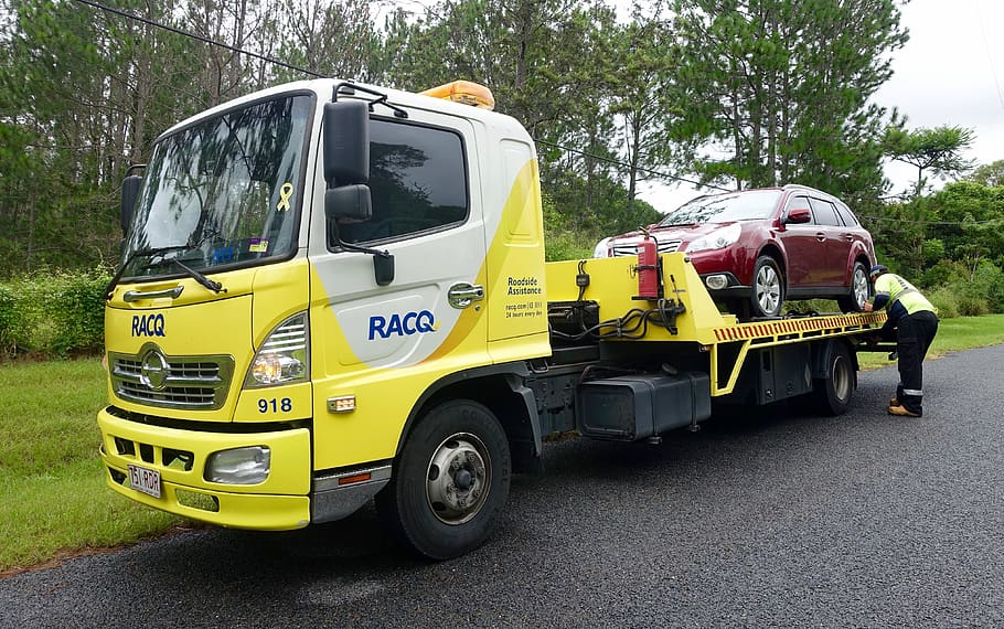 A tow truck removing a junk car from a driveway in Rosedale, New York.