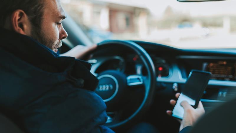 Man looking at cell phone while driving