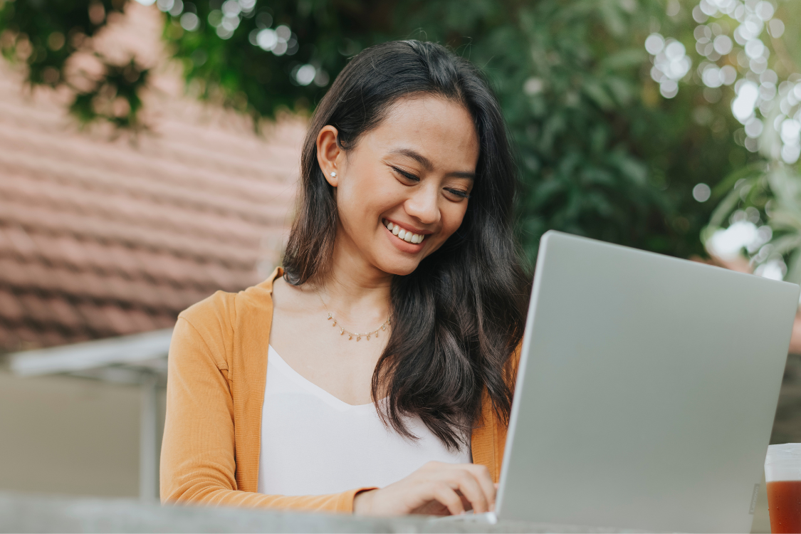 Smiling Filipina administrative assistant working outdoors on a laptop