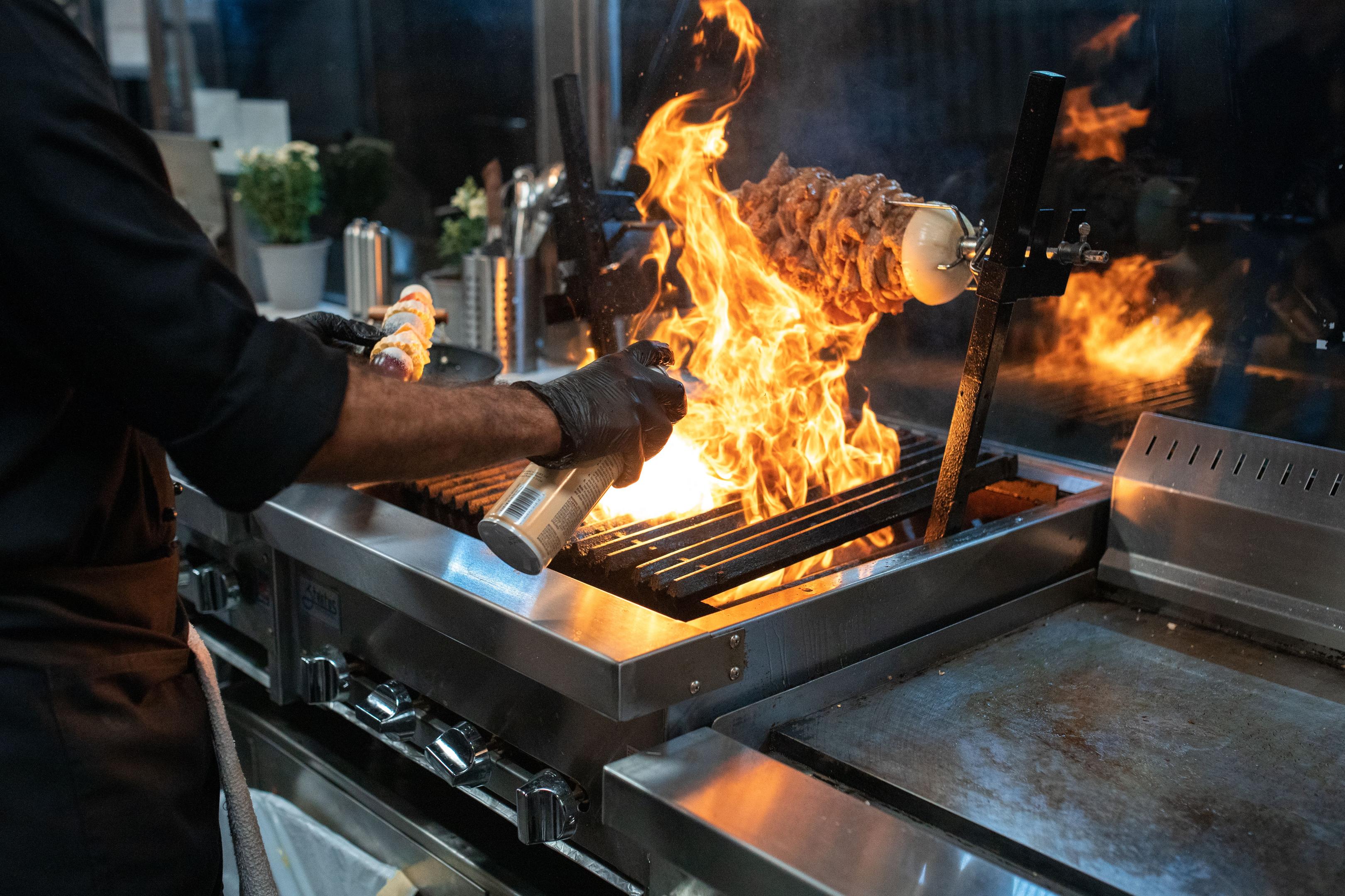The image captures a bustling California restaurant kitchen during peak dinner hours, where multiple cooks are diligently working at their stations, and a line of tickets is visible on the pass, highlighting the fast-paced environment of the hospitality industry. The scene reflects the teamwork and efficiency required in the restaurant industry to serve customers effectively.